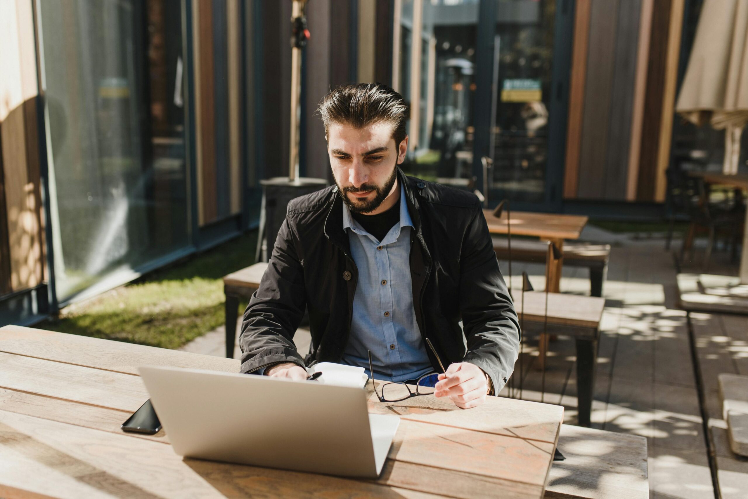 Man outside at restaurant picnic table reviewing numbers